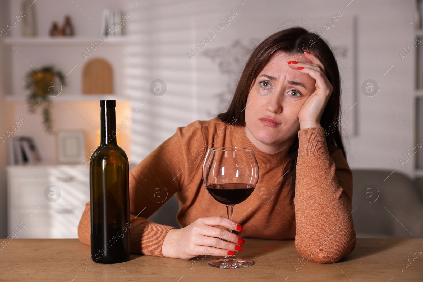 Photo of Alcohol addiction. Miserable woman with wine at table indoors