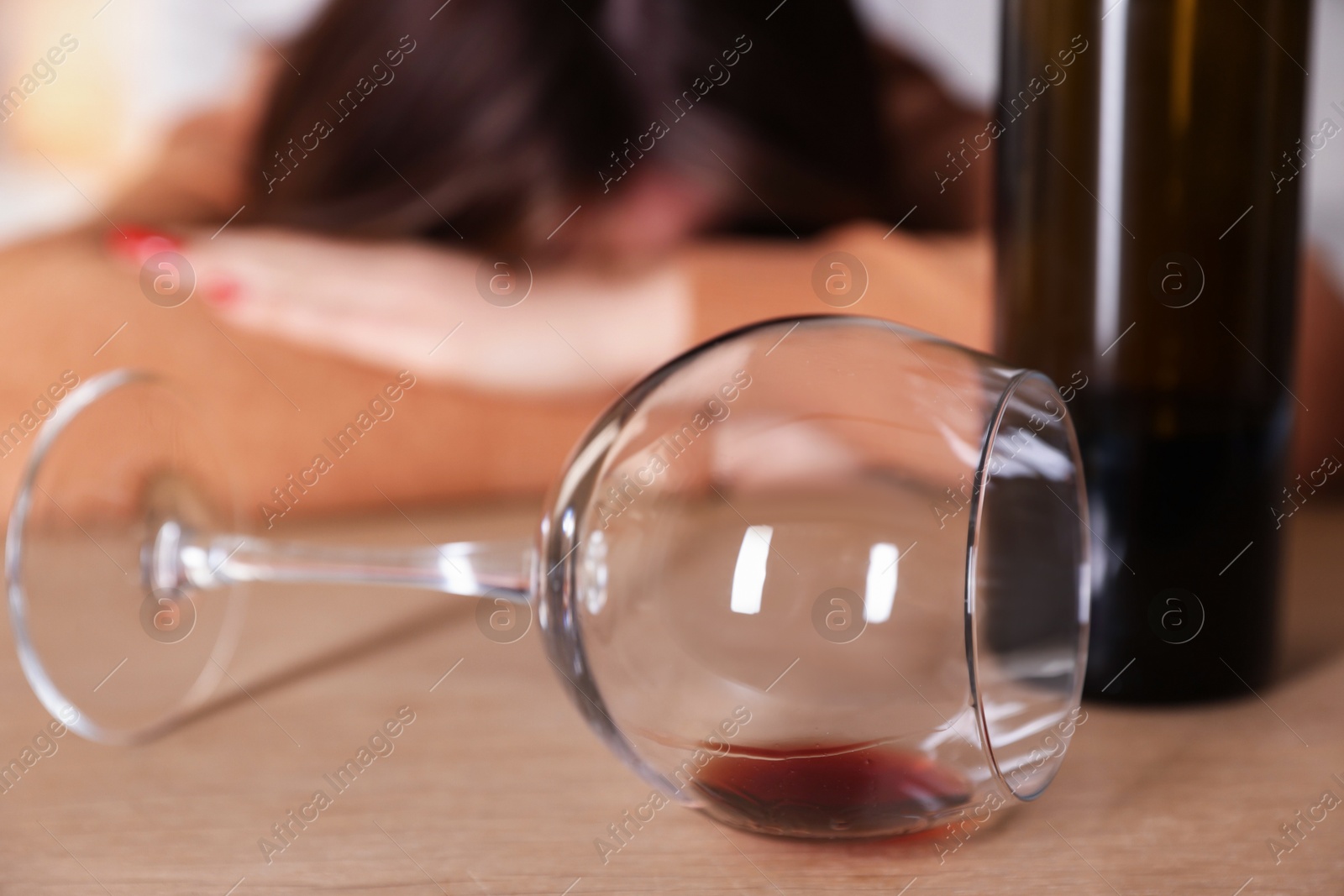 Photo of Alcohol addiction. Miserable woman with wine at table indoors, selective focus