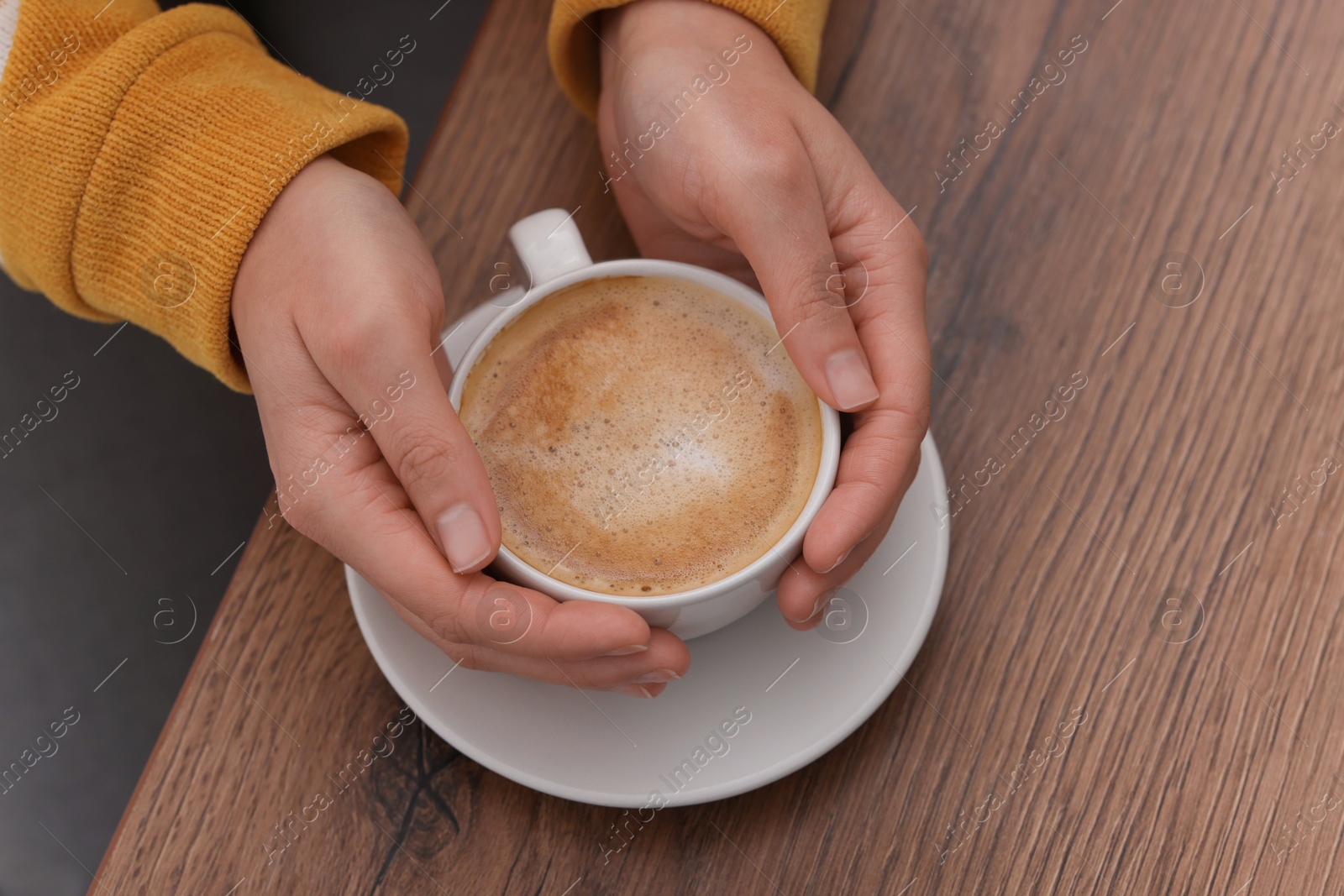 Photo of Coffee break. Woman with cup of hot drink at wooden table, closeup