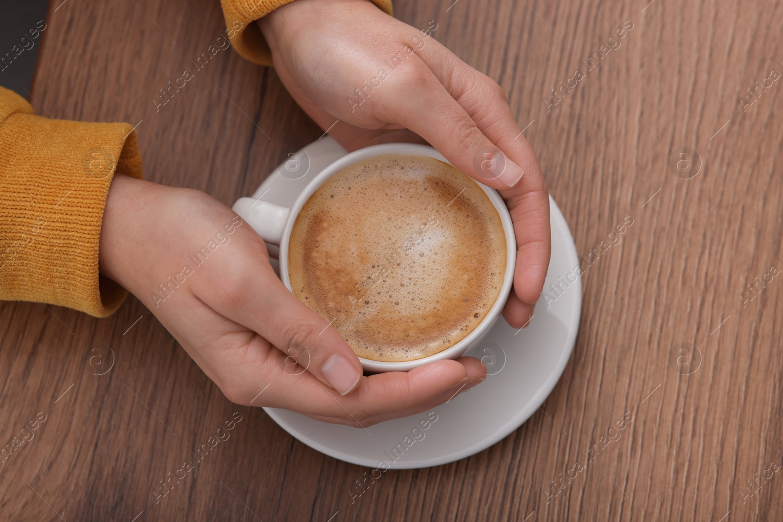 Photo of Coffee break. Woman with cup of hot drink at wooden table, top view