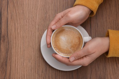 Photo of Coffee break. Woman with cup of hot drink at wooden table, top view. Space for text