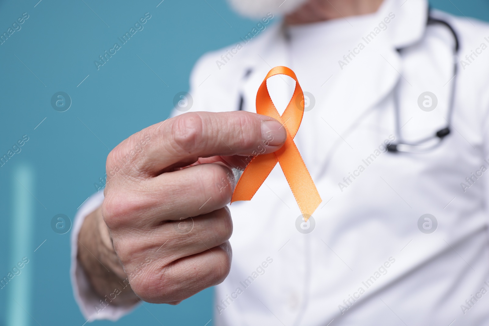 Photo of Multiple Sclerosis awareness. Doctor with orange ribbon on light blue background, closeup