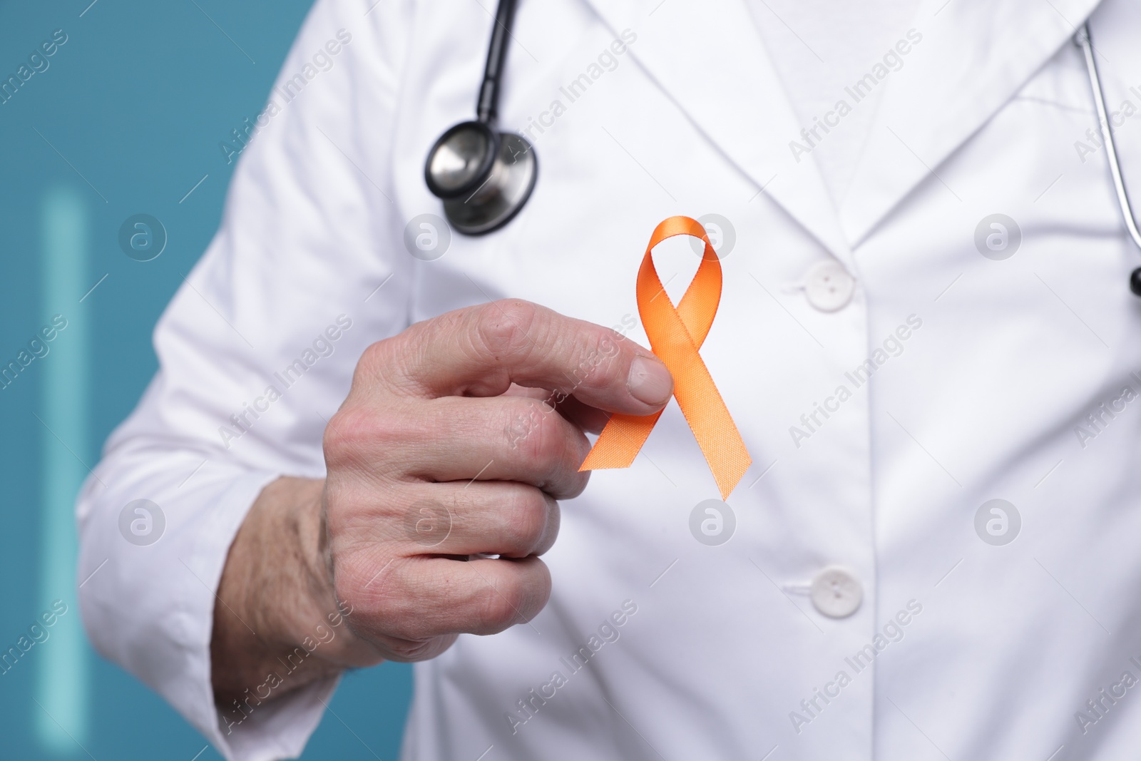 Photo of Multiple Sclerosis awareness. Doctor with orange ribbon on light blue background, closeup