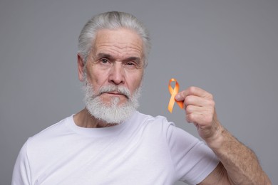 Photo of Multiple Sclerosis awareness. Senior man with orange ribbon on grey background