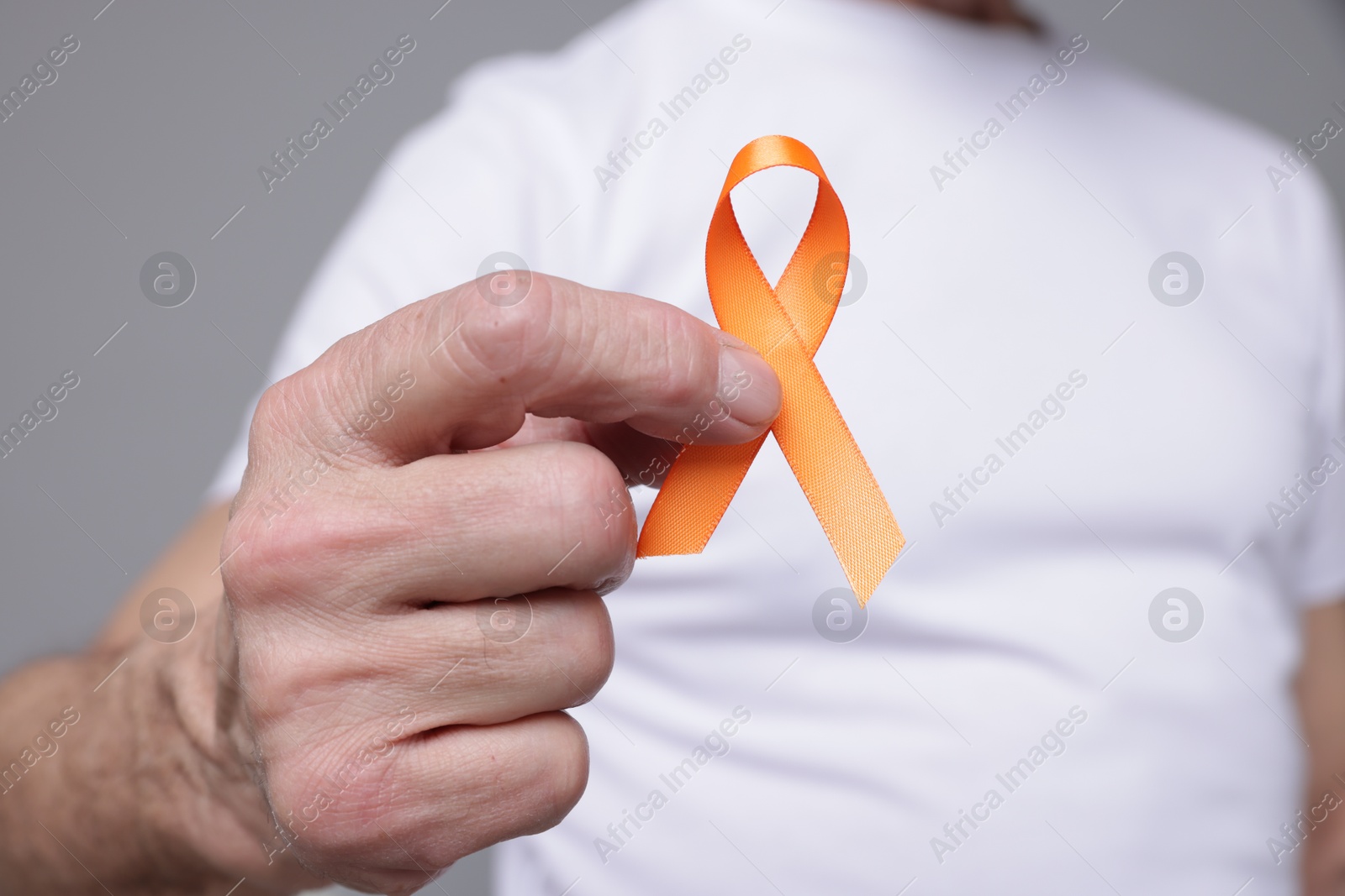 Photo of Multiple Sclerosis awareness. Senior man with orange ribbon on grey background, closeup