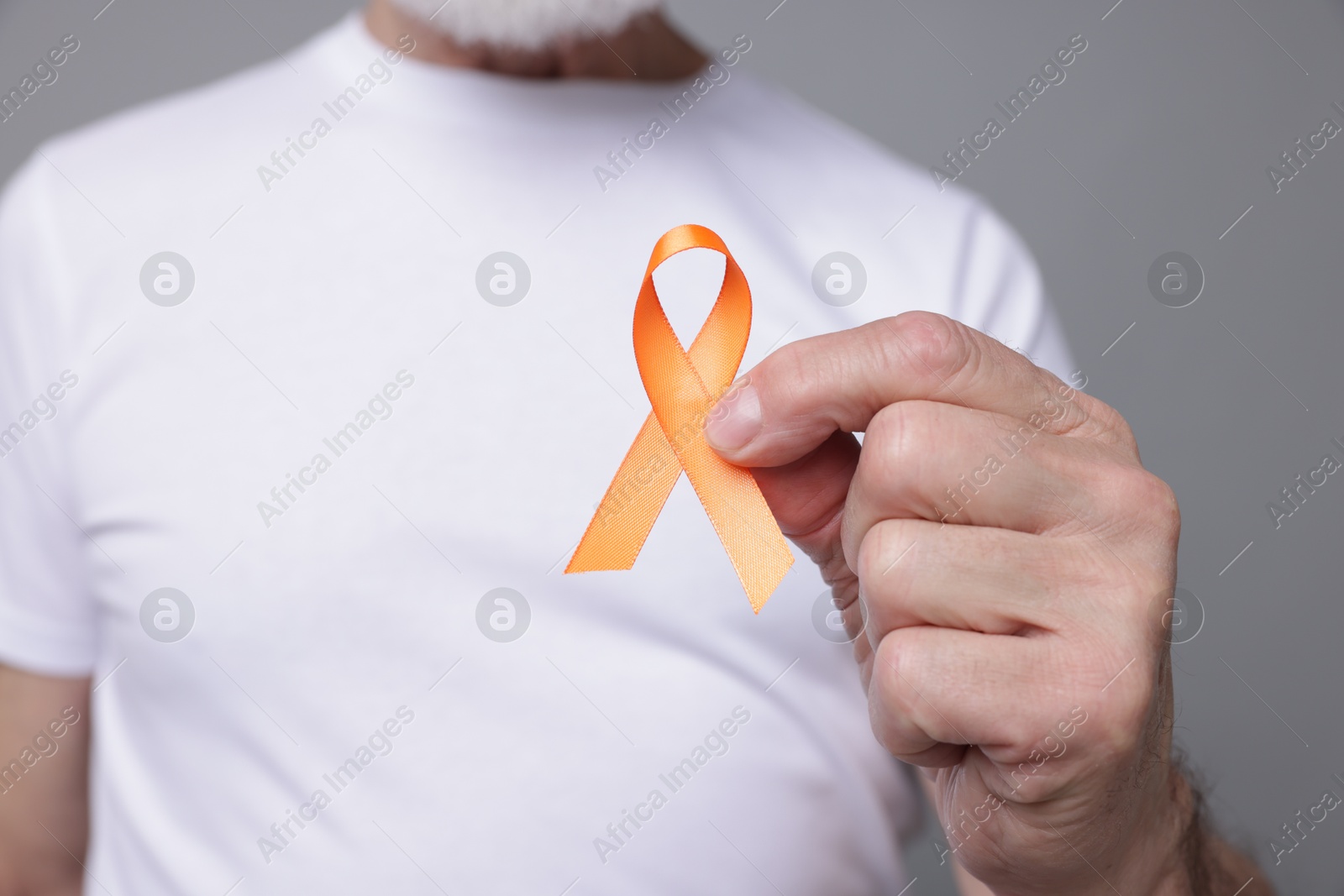 Photo of Multiple Sclerosis awareness. Senior man with orange ribbon on grey background, closeup