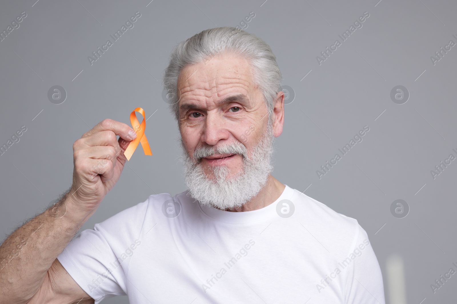 Photo of Multiple Sclerosis awareness. Senior man with orange ribbon on grey background