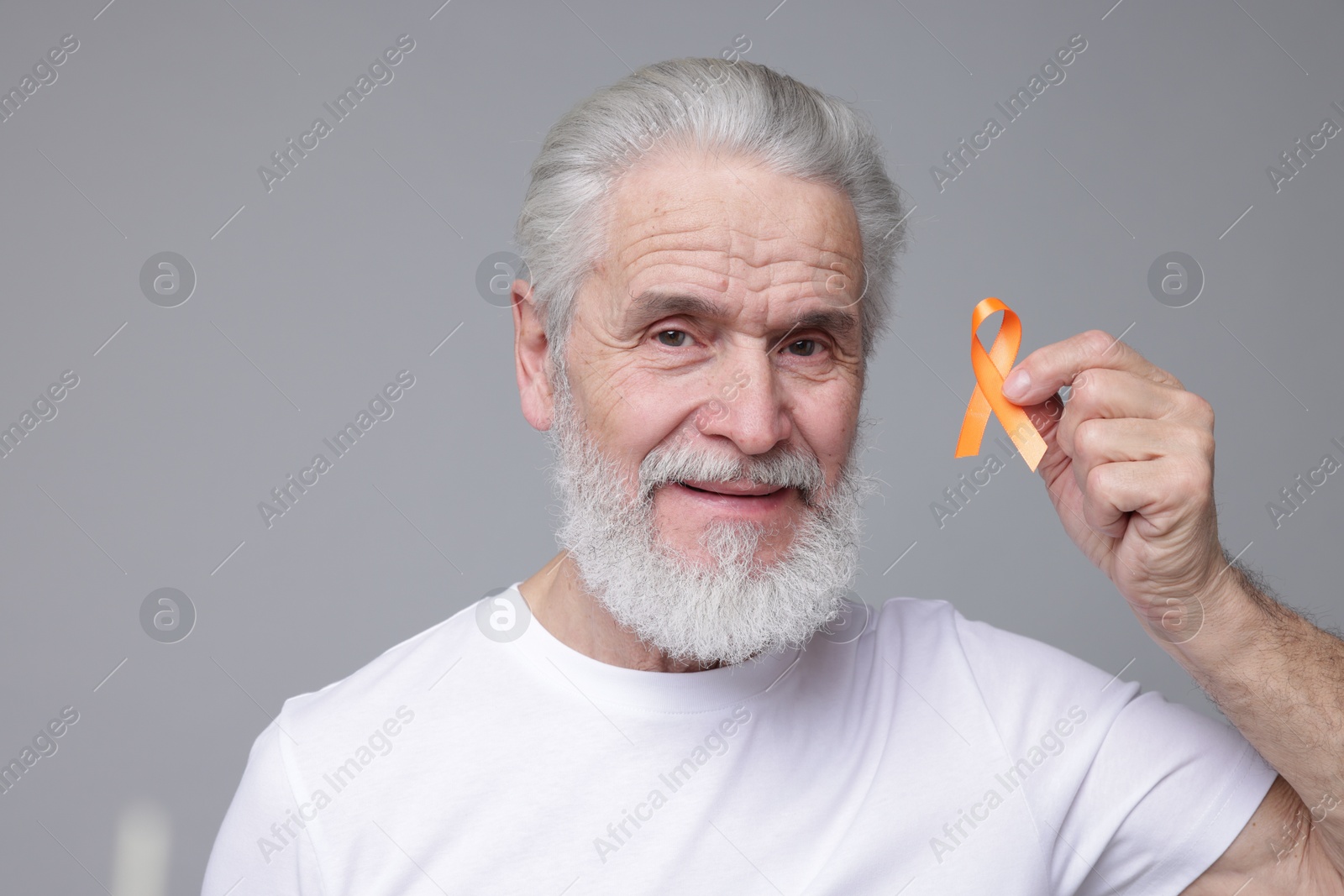 Photo of Multiple Sclerosis awareness. Senior man with orange ribbon on grey background