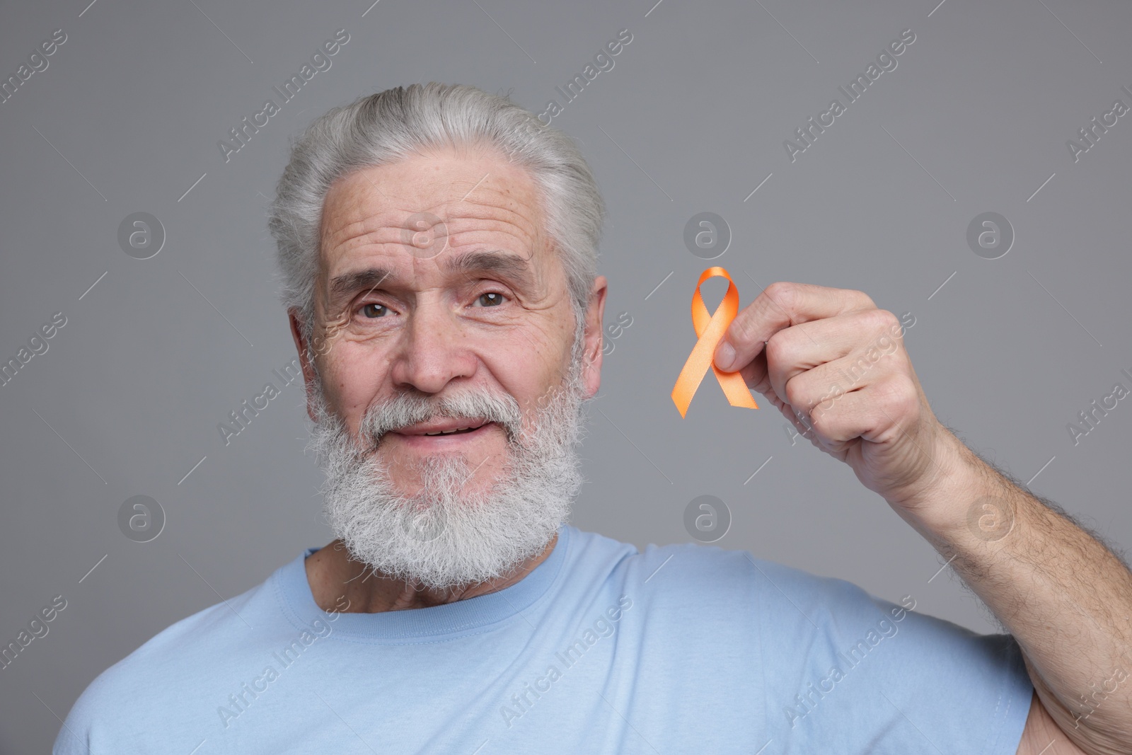 Photo of Multiple Sclerosis awareness. Senior man with orange ribbon on grey background