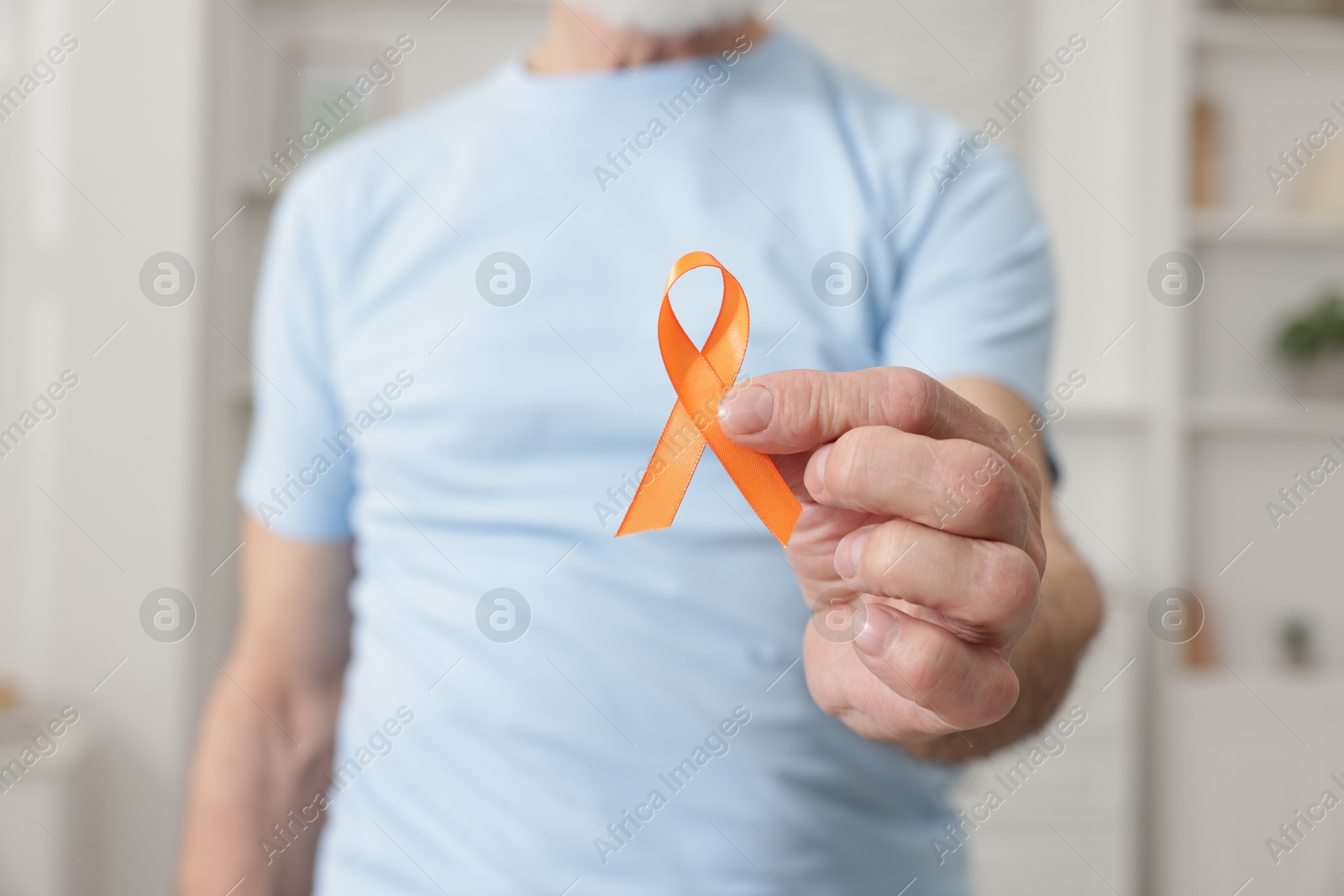 Photo of Multiple Sclerosis awareness. Senior man with orange ribbon indoors, closeup