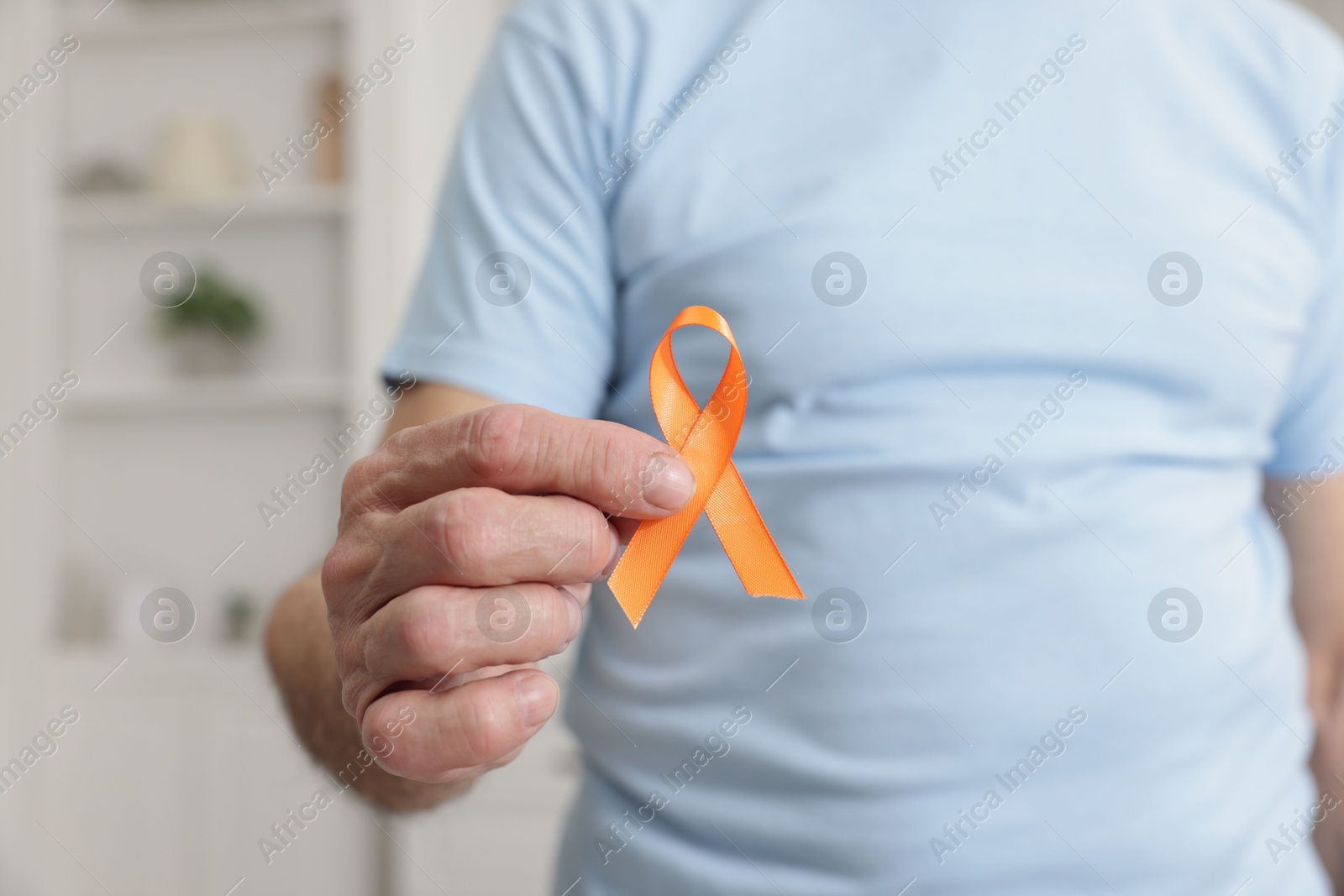 Photo of Multiple Sclerosis awareness. Senior man with orange ribbon indoors, closeup