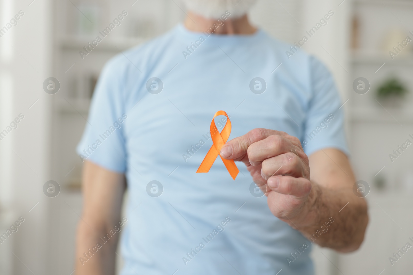 Photo of Multiple Sclerosis awareness. Senior man with orange ribbon indoors, closeup