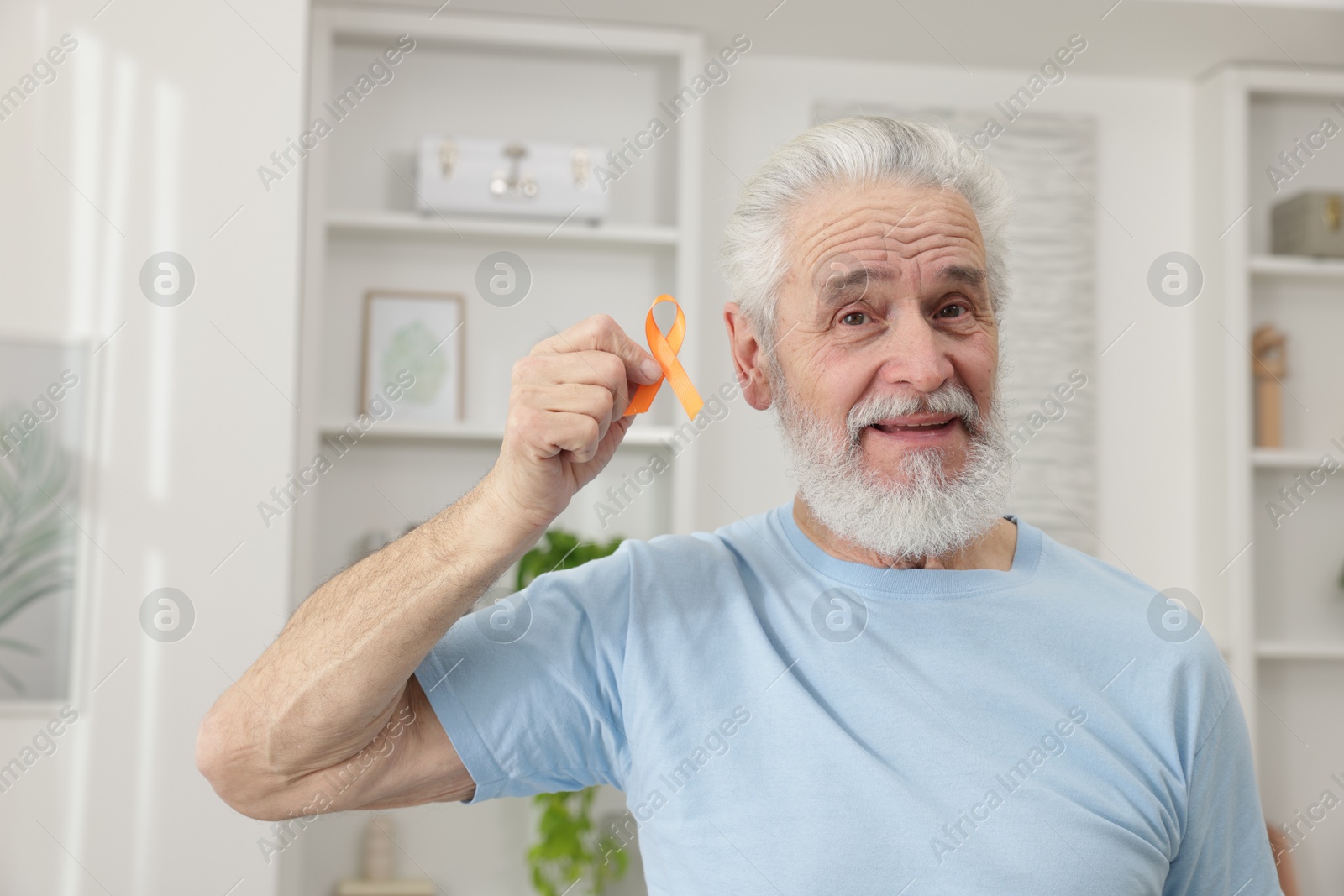 Photo of Multiple Sclerosis awareness. Senior man with orange ribbon indoors