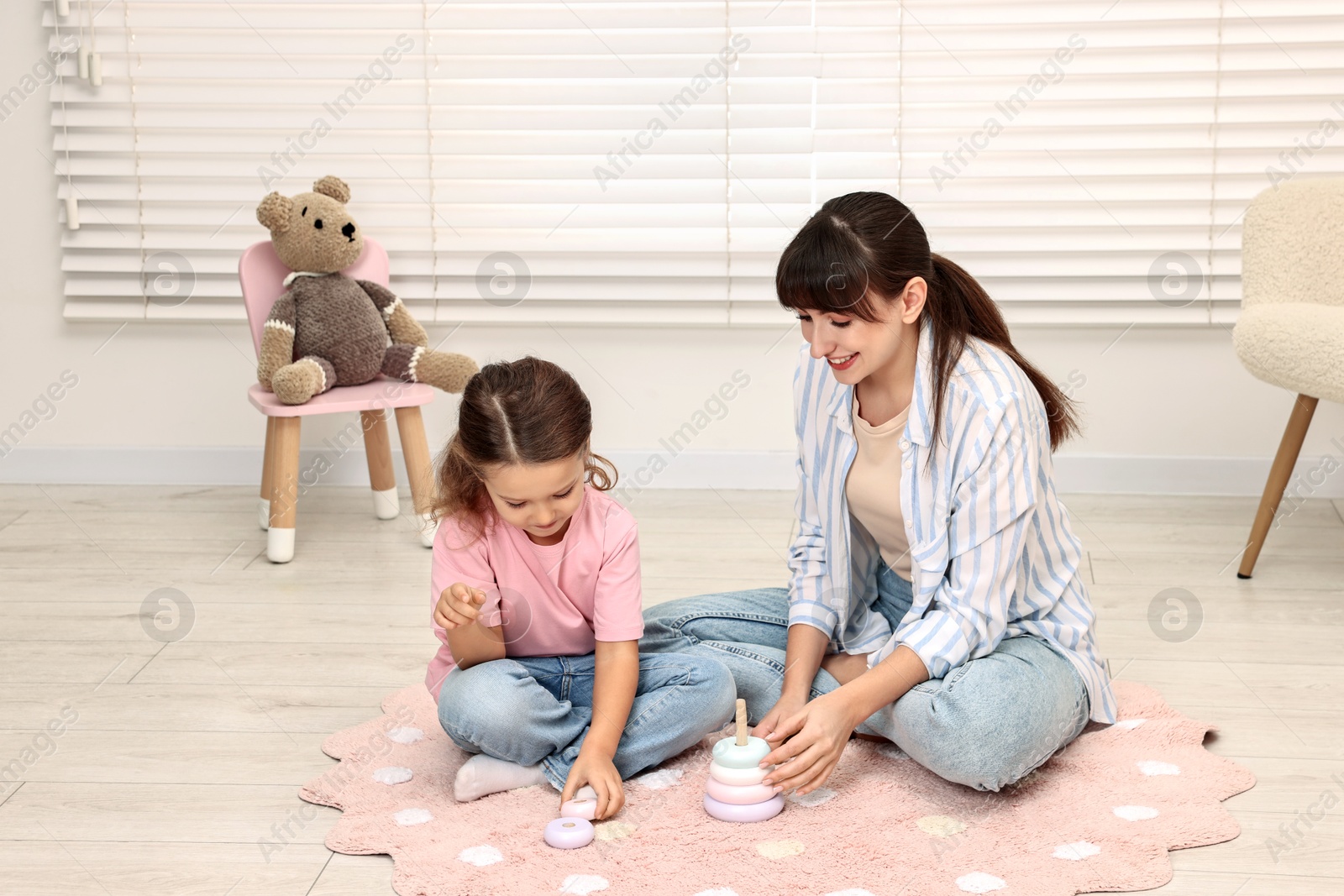 Photo of Autism therapy. Smiling psychologist and little girl playing with educational toy in mental health center