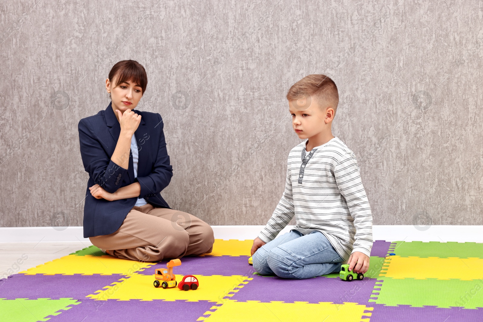 Photo of Psychologist observing little boy playing in autism treatment center