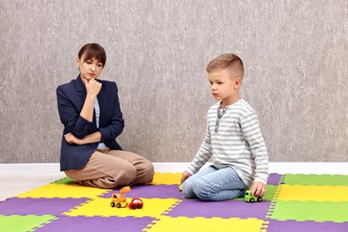 Photo of Psychologist observing little boy playing in autism treatment center