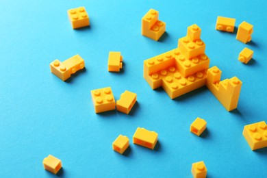 Photo of Constructor toy. Many yellow building blocks on light blue background