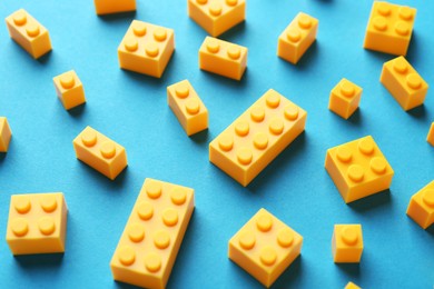 Photo of Constructor toy. Many yellow building blocks on light blue background