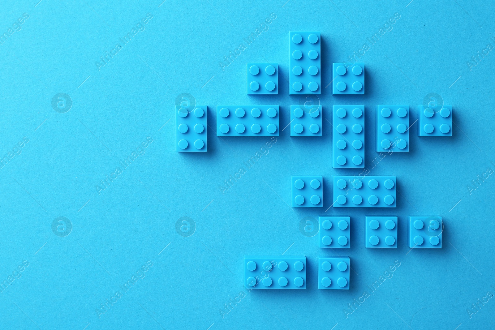 Photo of Constructor toy. Many building blocks on light blue background, flat lay. Space for text