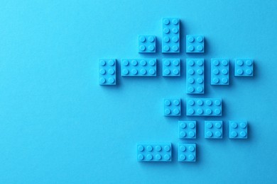 Photo of Constructor toy. Many building blocks on light blue background, flat lay. Space for text