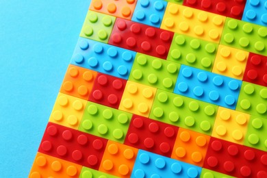 Photo of Constructor toy. Many colorful building blocks on light blue background, top view