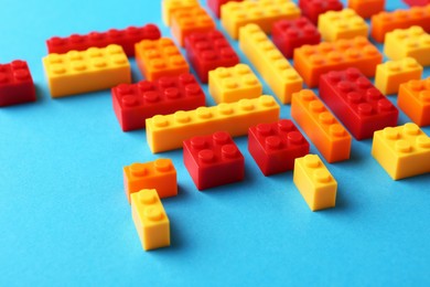 Photo of Constructor toy. Many colorful building blocks on light blue background, closeup