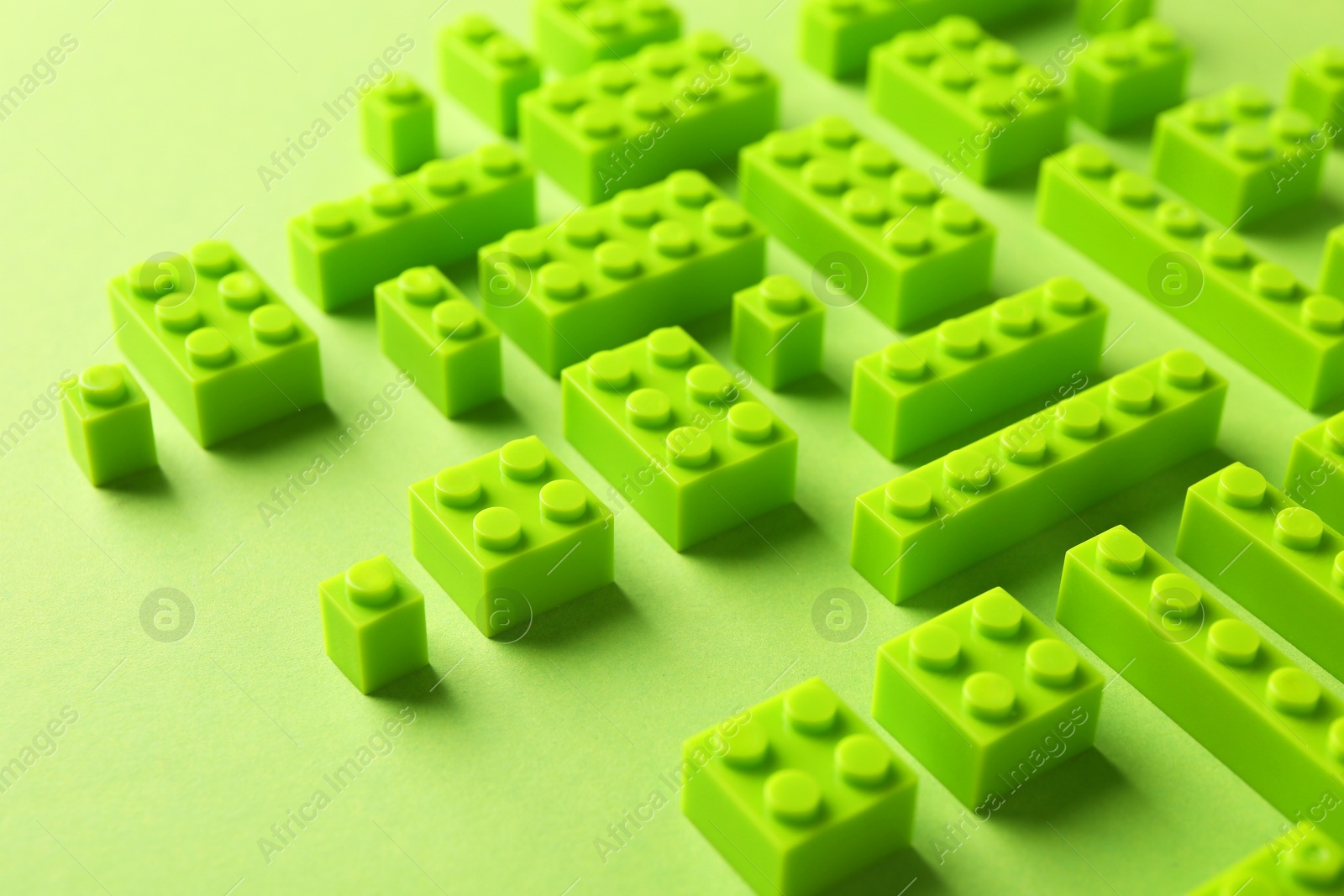 Photo of Constructor toy. Many building blocks on light green background, closeup