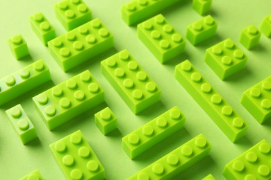 Photo of Constructor toy. Many building blocks on light green background, above view