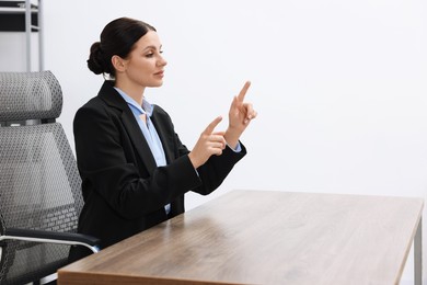 Beautiful woman pointing at something in office, space for text