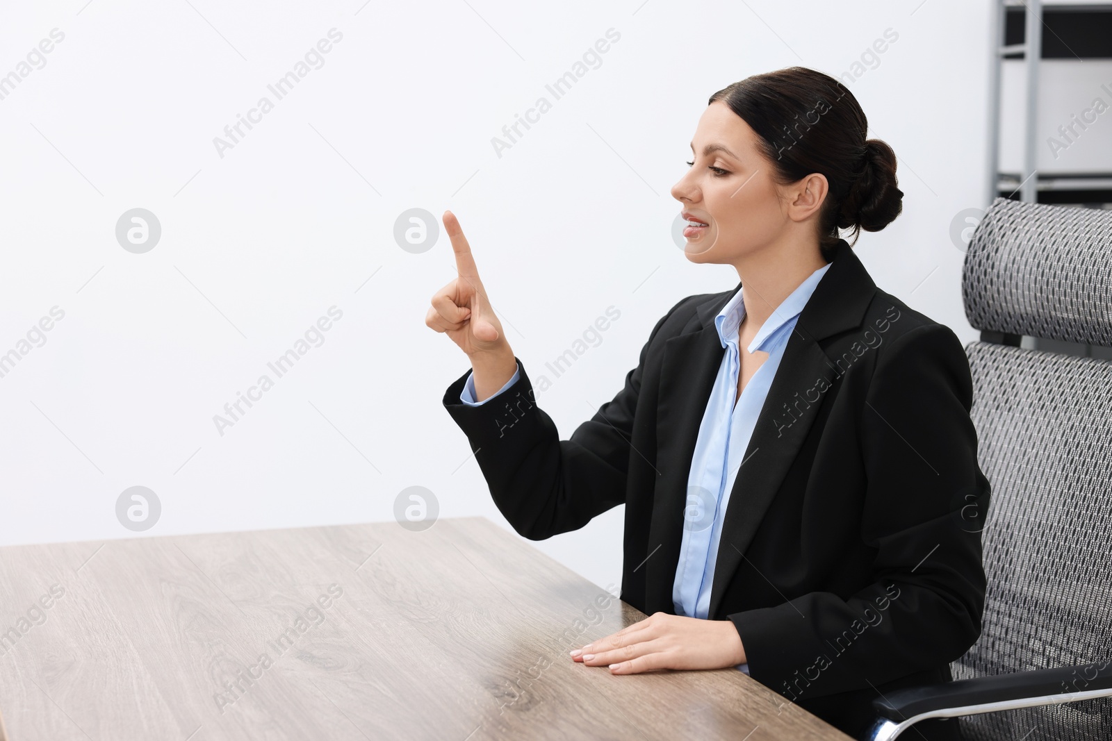 Photo of Beautiful woman pointing at something in office, space for text