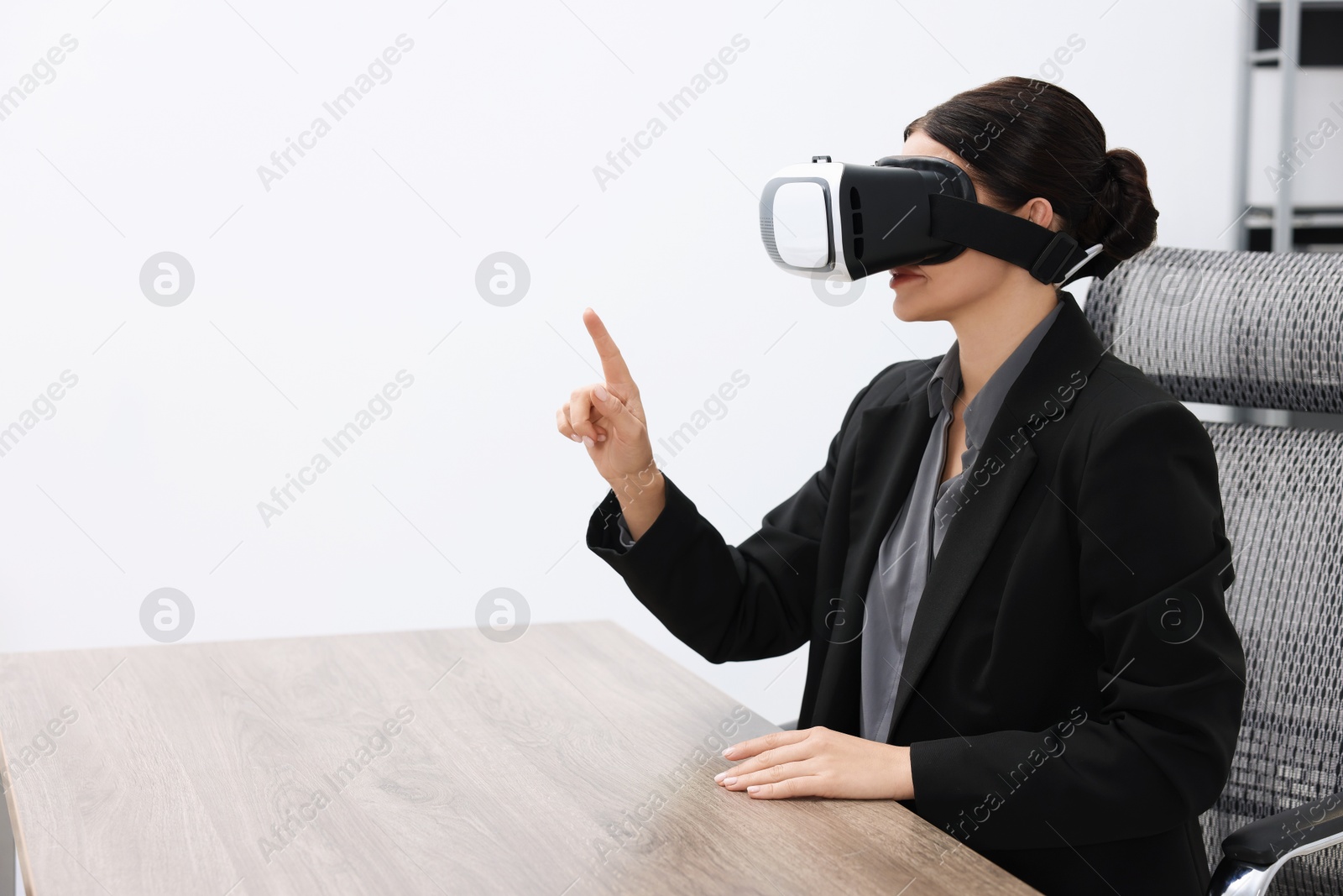 Photo of Woman using virtual reality headset in office, space for text