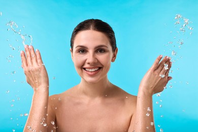 Photo of Smiling woman washing her face on light blue background