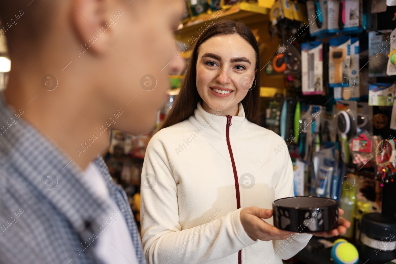 Photo of Young couple choosing feeding bowl in pet shop, selective focus