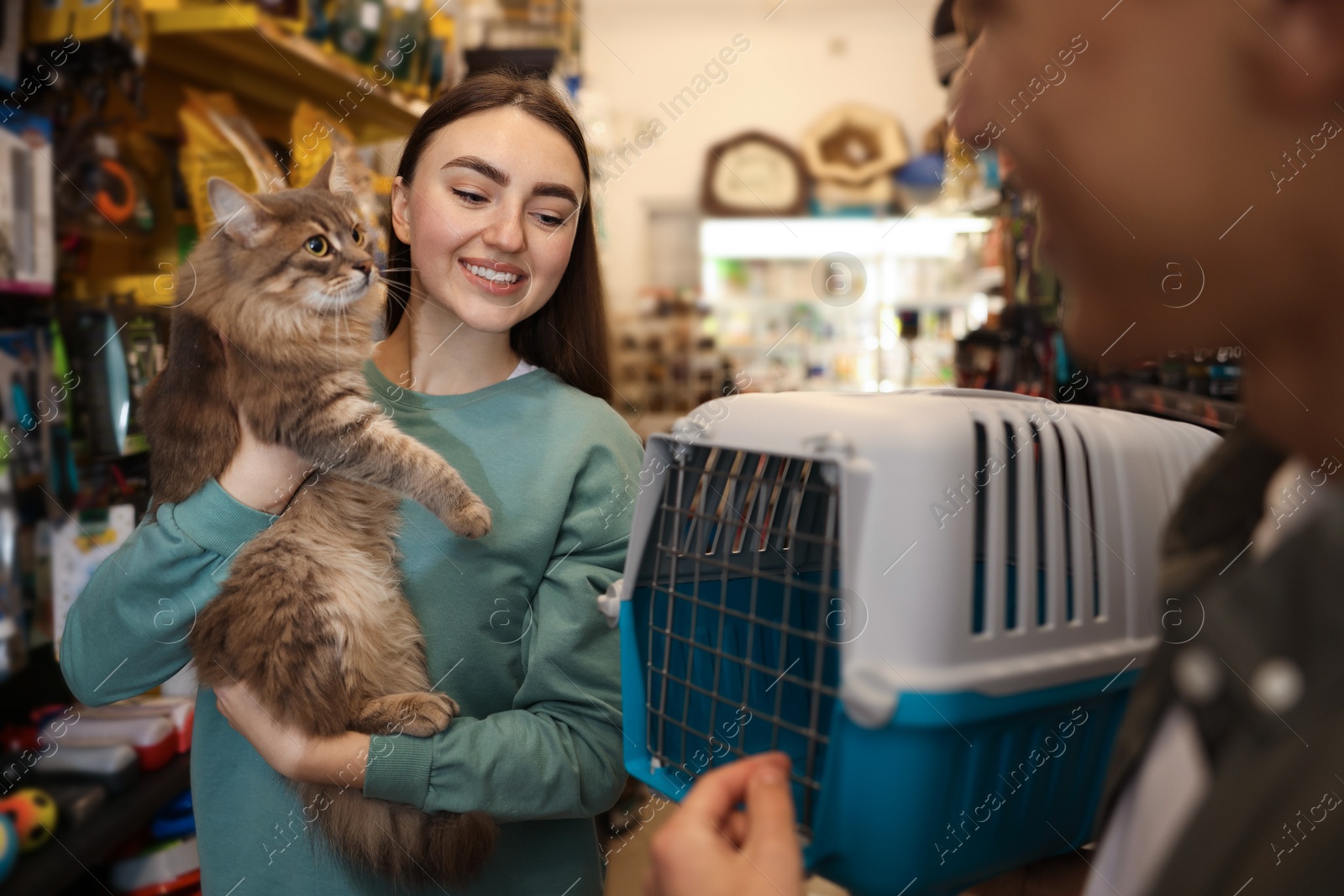 Photo of Couple choosing carrier for their cute cat in pet shop, selective focus