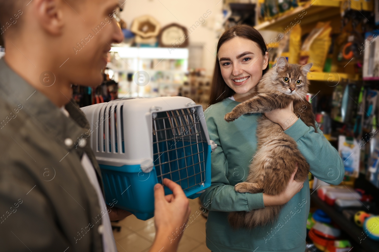 Photo of Couple choosing carrier for their cute cat in pet shop, selective focus