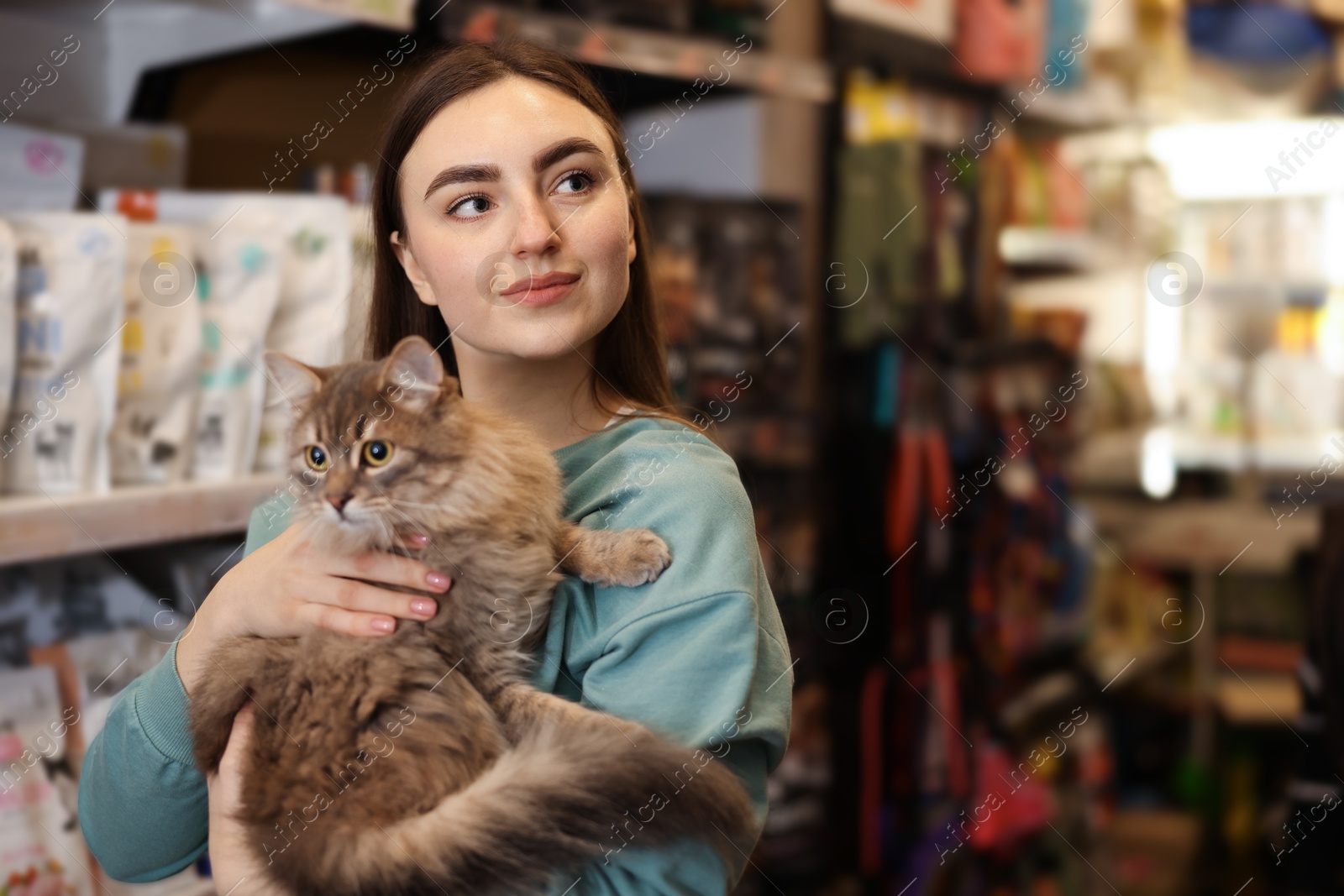 Photo of Happy woman with her cute cat in pet shop. Space for text