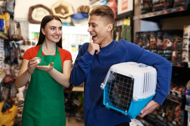 Pet shop worker recommending food for man's cute cat indoors