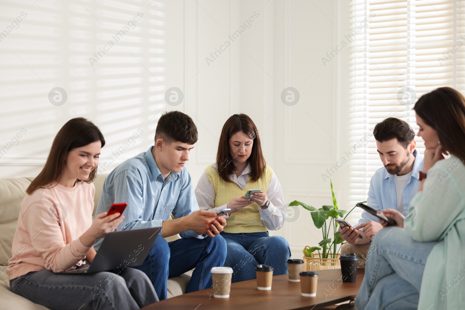 Photo of Internet addiction. Group of friends with gadgets and coffee at table indoors