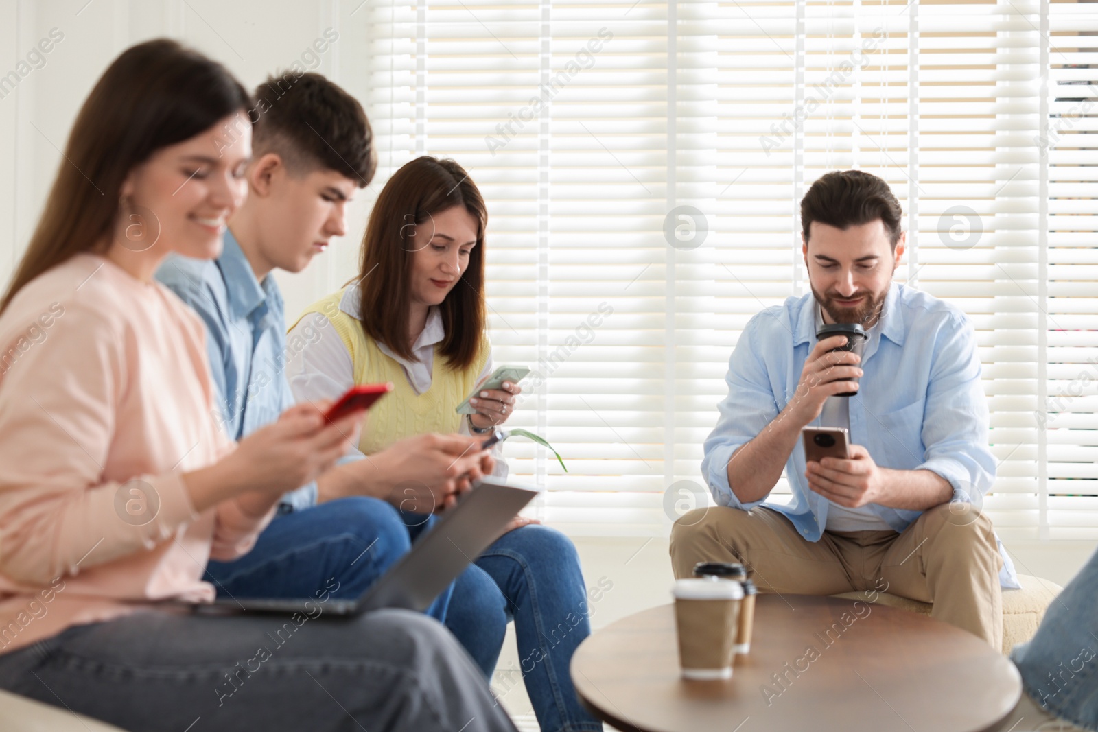 Photo of Internet addiction. Group of friends with gadgets and coffee at table indoors