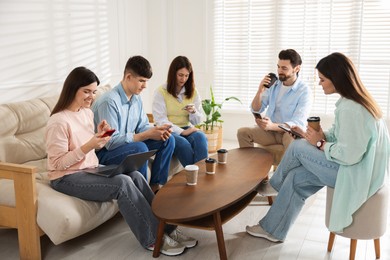 Internet addiction. Group of friends with gadgets and coffee at table indoors