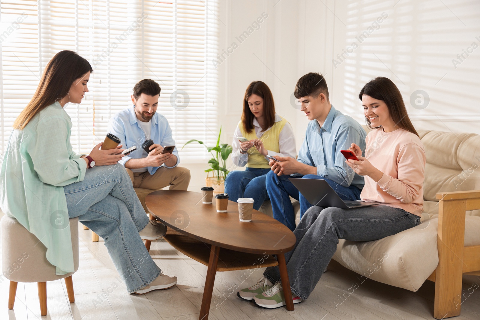 Photo of Internet addiction. Group of friends with gadgets and coffee at table indoors