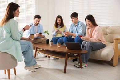 Photo of Internet addiction. Group of friends with gadgets and coffee at table indoors