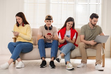 Photo of Internet addiction. Group of people with gadgets on sofa indoors