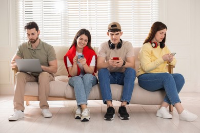 Photo of Internet addiction. Group of people with gadgets on sofa indoors