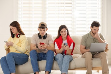 Internet addiction. Group of people with gadgets on sofa indoors