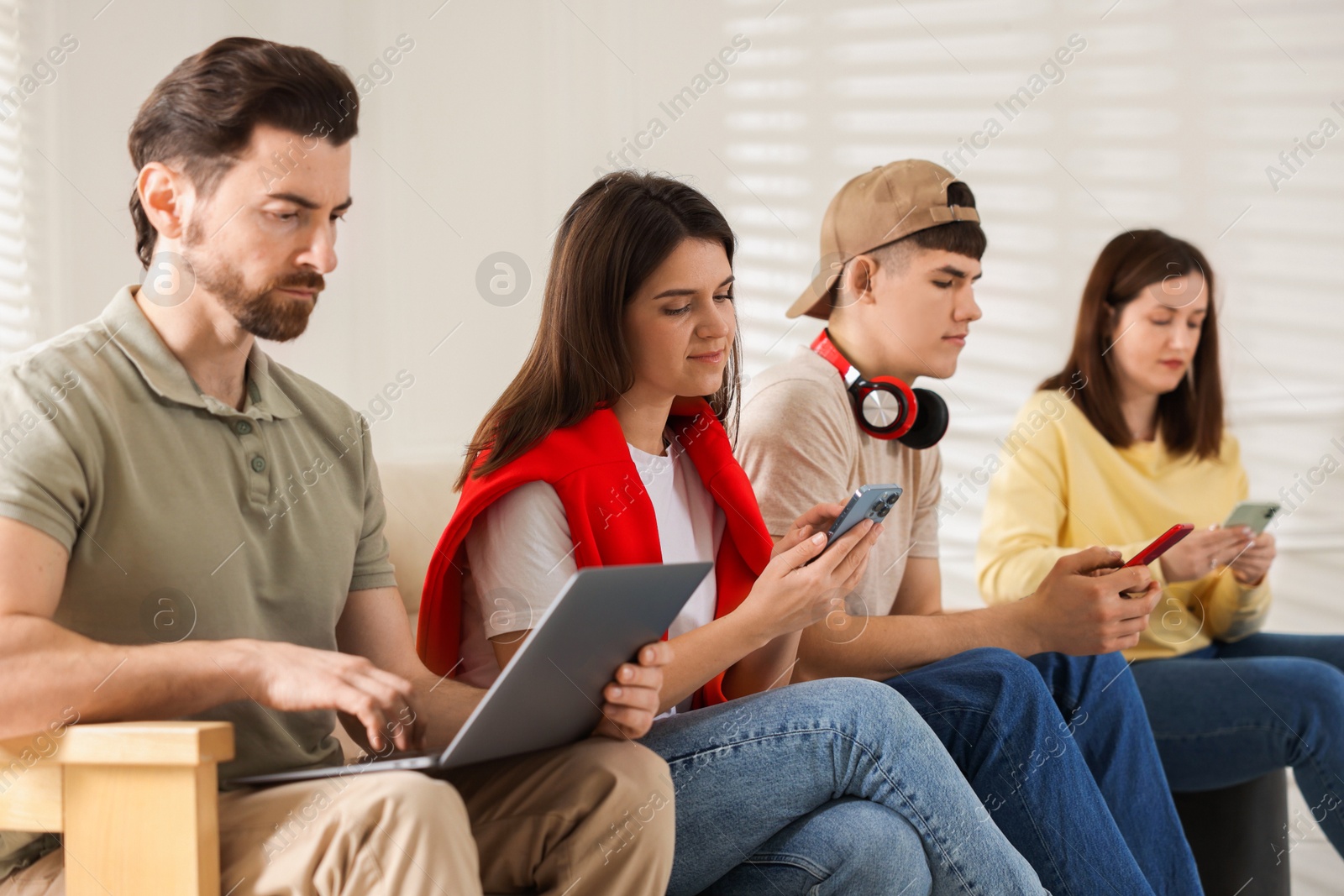 Photo of Internet addiction. Group of people with gadgets on sofa indoors