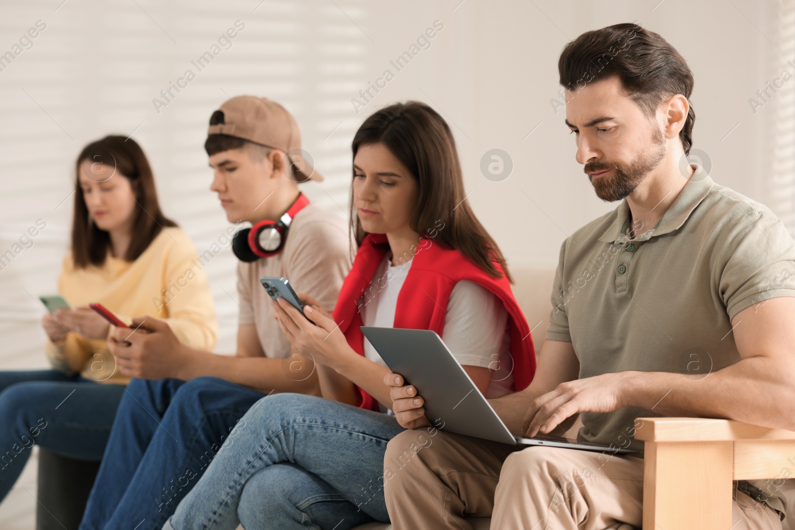 Photo of Internet addiction. Group of people with gadgets on sofa indoors