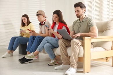 Photo of Internet addiction. Group of people with gadgets on sofa indoors