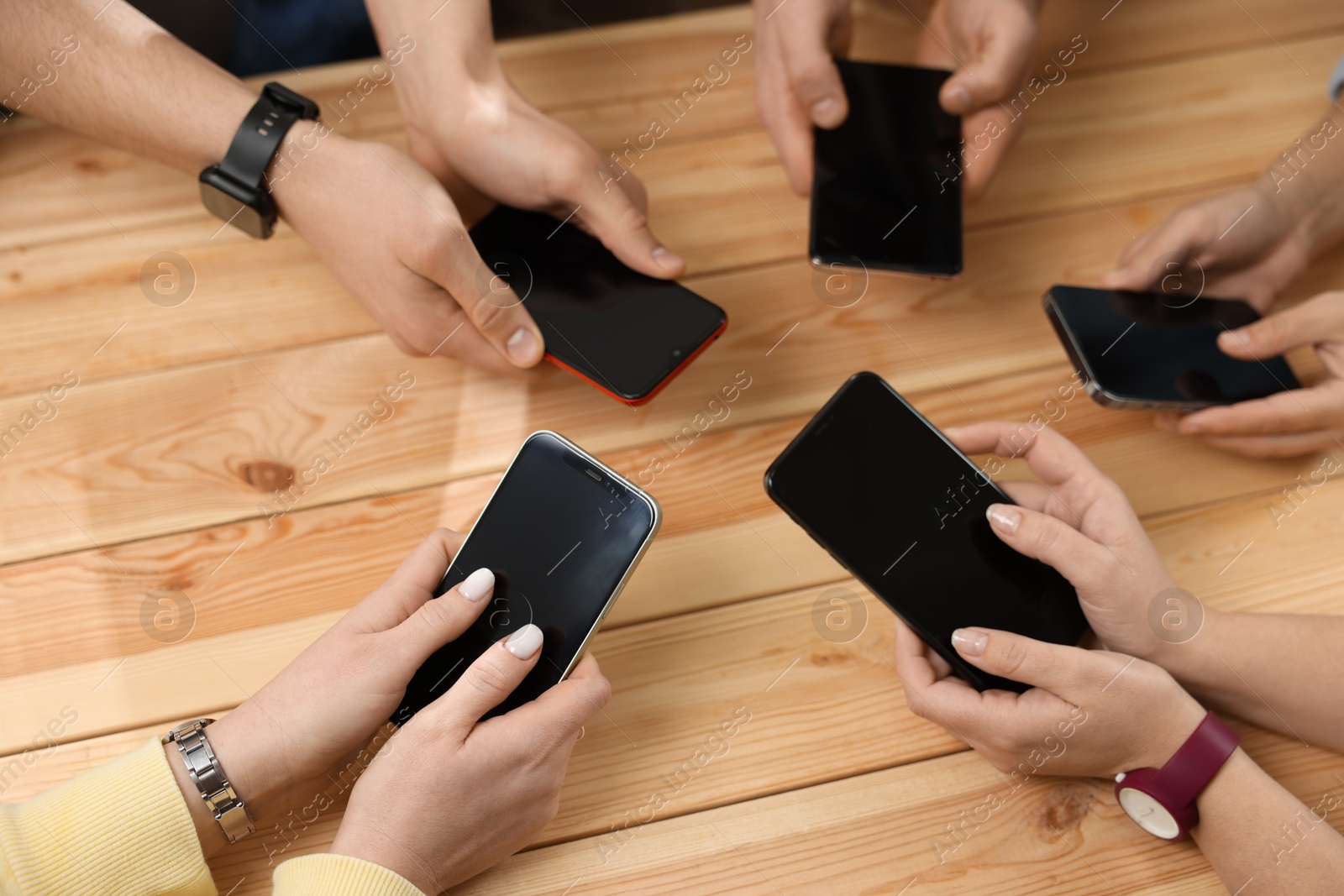 Photo of Internet addiction. People with smartphones at wooden table, top view