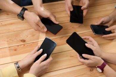 Photo of Internet addiction. People with smartphones at wooden table, top view